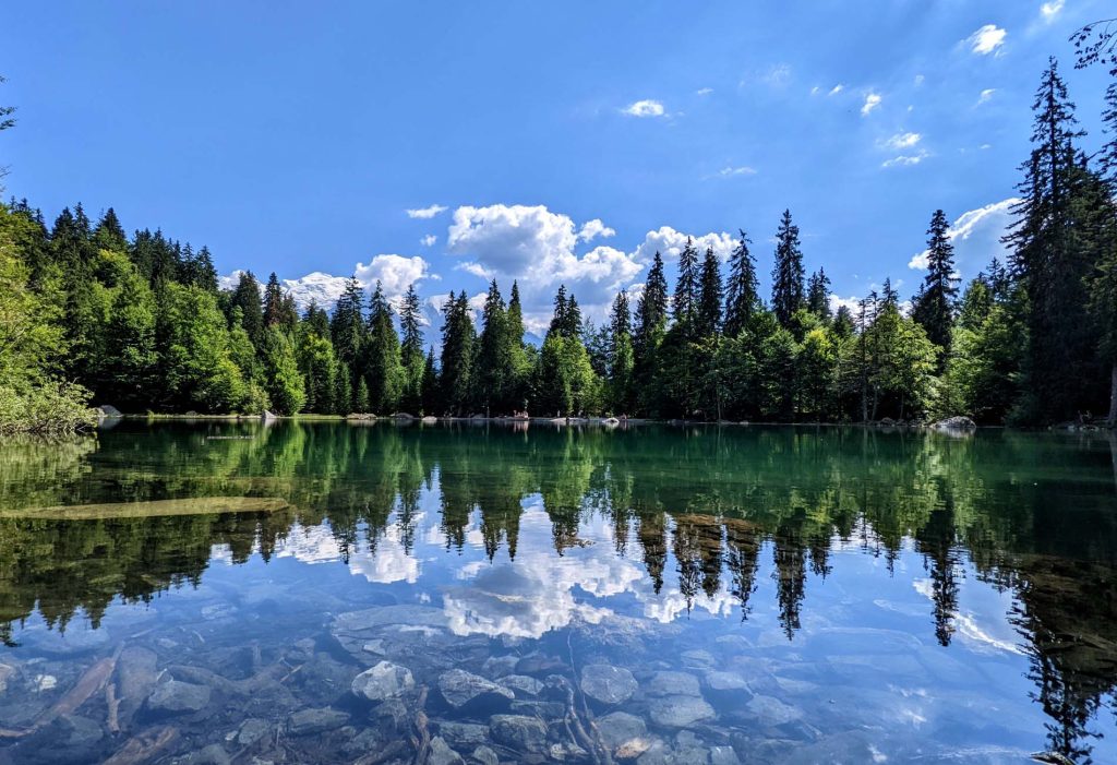 Paysage d'un lac entourés d'arbres par beau temps. Le paysage se reflète dans le lac.