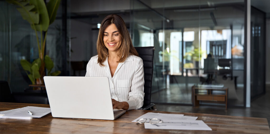 Femme d'affaires utilisant un ordinateur portable pour travailler à une table dans un bureau.