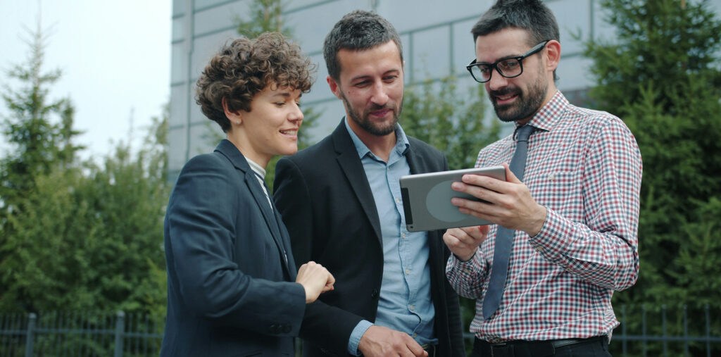 Trois salariés regardant une tablette à l'extérieur